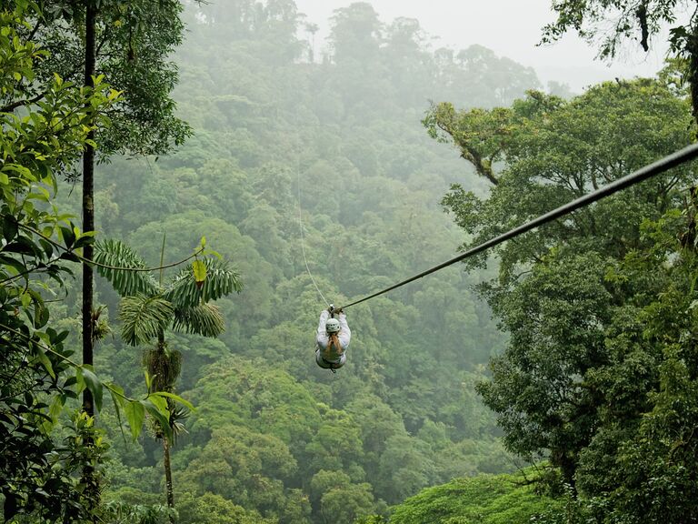 Costa Rica Honeymoon - A person zip lining across a rainforest in Costa Rica