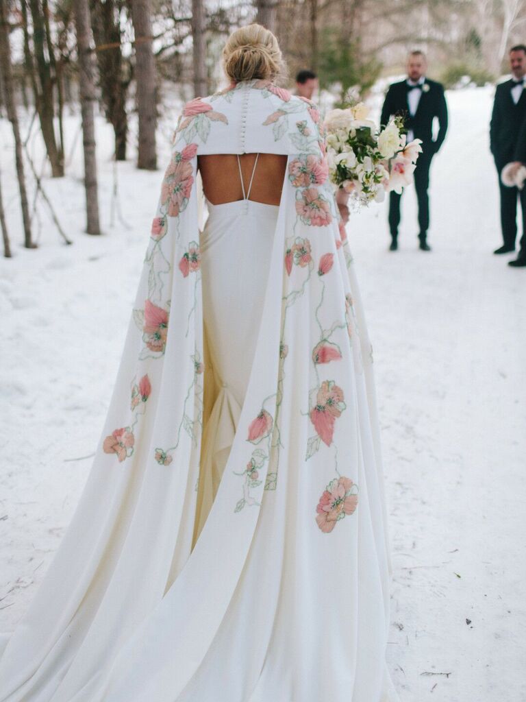 Bride wearing white wedding dress with pink floral cape