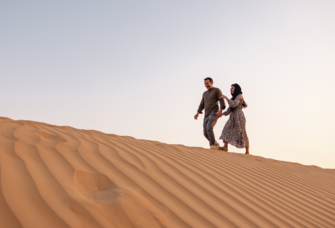 Couple holding hands walking through desert in Dubai, Dubai proposal ideas