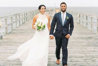 Couple holding hands while walking on a pier at their Delaware wedding