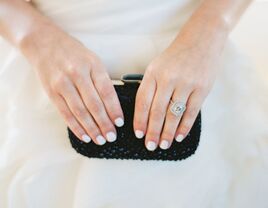 Bride with engagement ring holding clutch