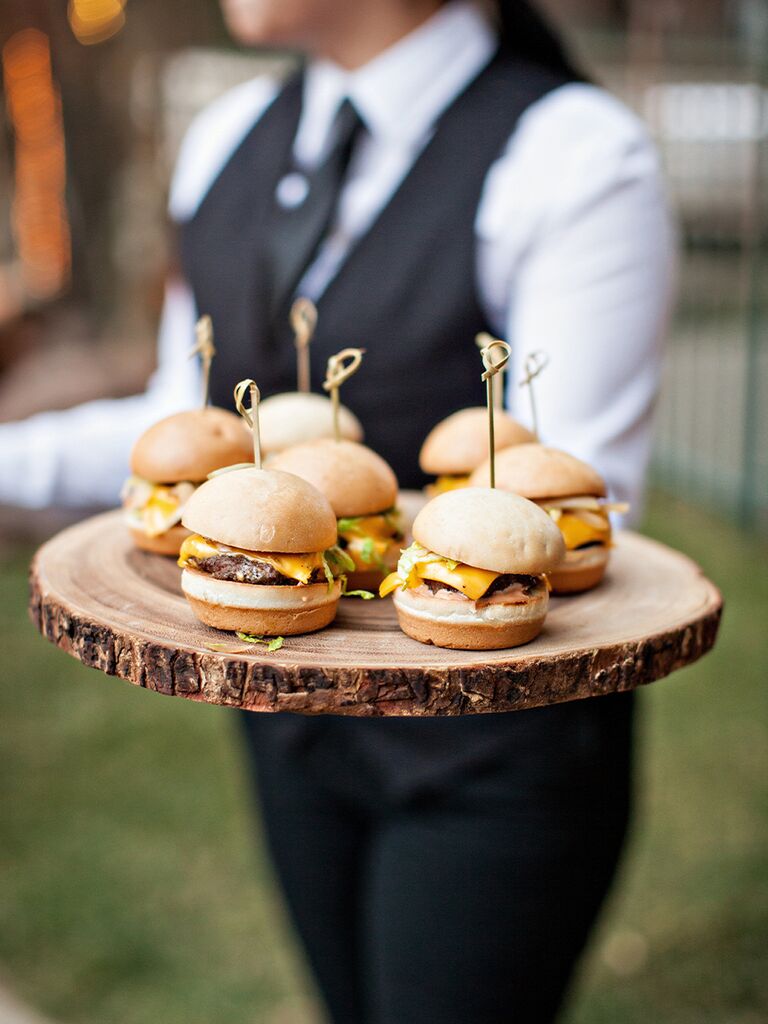 Server holding tray of mini cheeseburgers