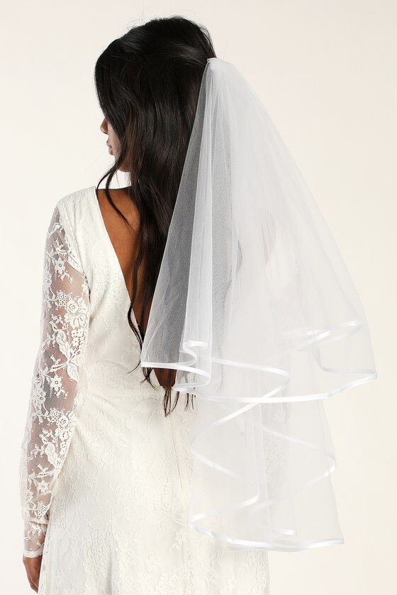Model wears a sheer veil with satin trim. 