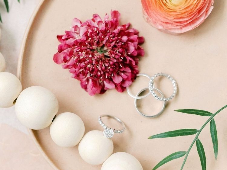 Flatlay with engagement rings and pink scabiosa blooms 