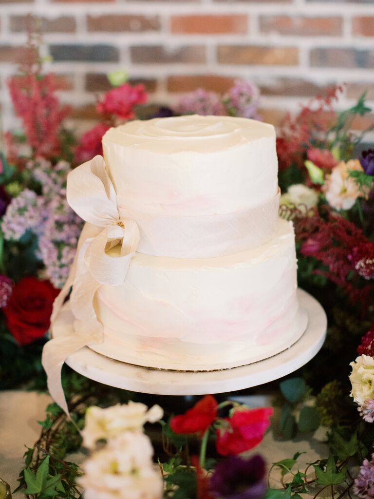 two tier buttercream wedding cake with blush silk ribbon tied in a bow around the middle tier