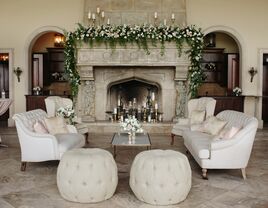 wedding lounge area with fireplace in the background decorated with greenery and gold candlesticks