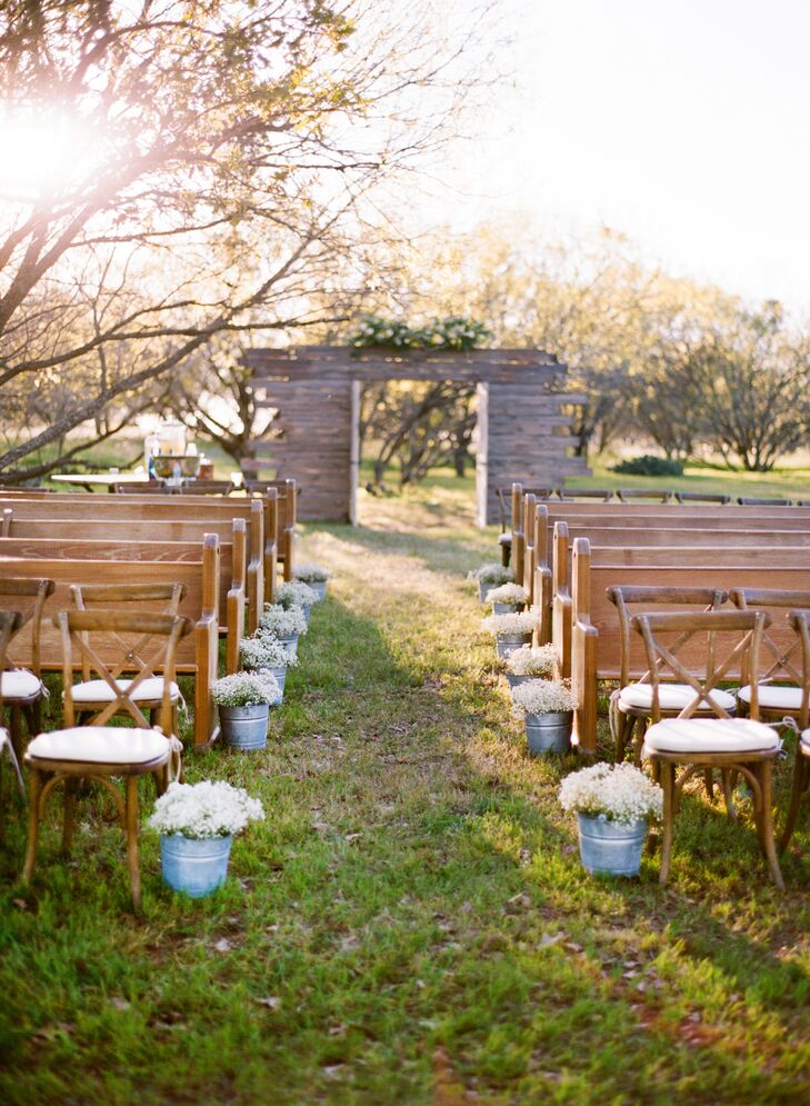 White flowers like baby's breath were used in the aisle, set inside galvanized pails as well as the tall upright amaranthus arrangements used in the reception. Florals were chosen to accent the natural Texas scenery.