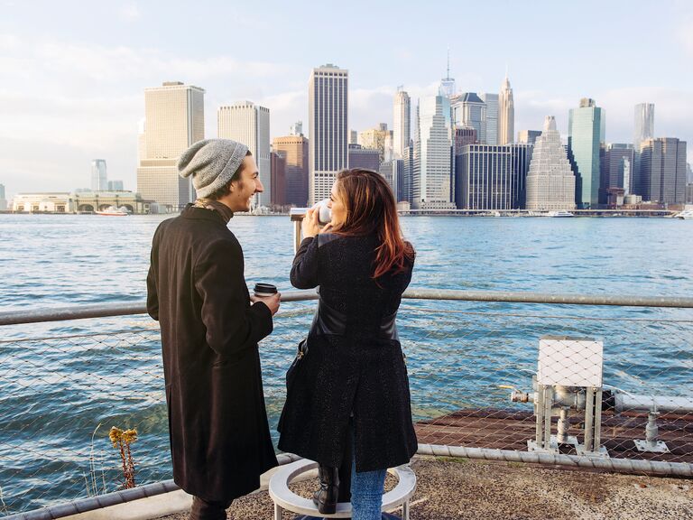 Rear view of young couple looking at Manhattan skyline from Brooklyn