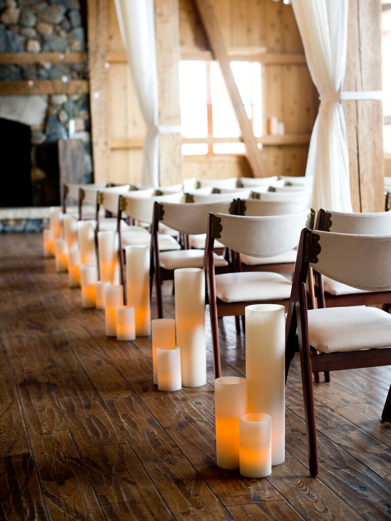 indoor wedding ceremony with white pillar candle aisle markers in varying heights