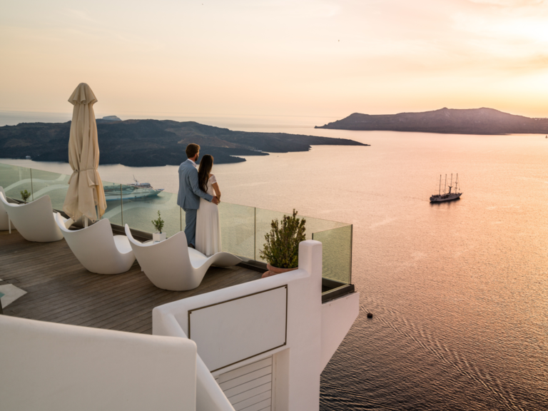 Couple standing on terrace at sunset in Greece