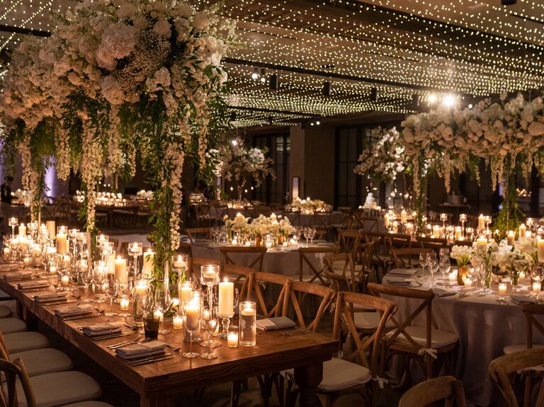 indoor wedding reception with tall centerpieces above long tables lined with candles down the center