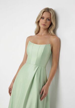 This strapless A-line bridesmaid dress in Mikado is pure drama and elegance in one. The corset-inspired bodice hugs the natural waist, while the scoop neckline keeps it modern and flirty. Crafted in Mikado, the fabric offers beautiful structure and a flattering fit, with soft pleats that sweep down the skirt into a playful slit, moving effortlessly with every step—perfect for twirling down the aisle or dancing the night away.