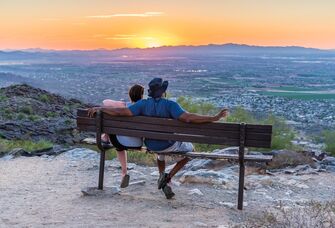 Couple sitting on a bench overlooking Phoenix, Arizona during sunset