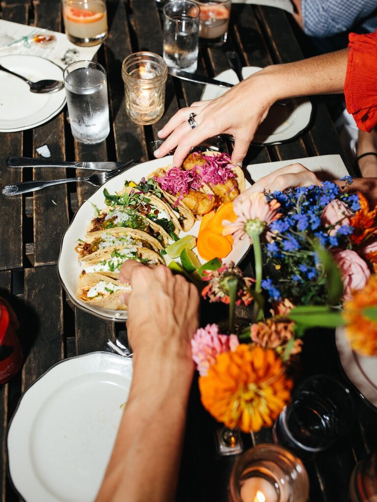 Reception table featuring a platter of various tacos served family-style. 