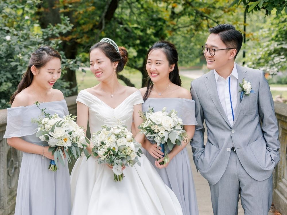 bride posing with bridesmaids and bridesman in gray outfits