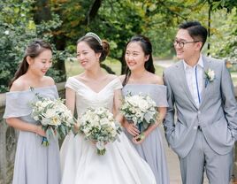 bride posing with bridesmaids and bridesman in gray outfits