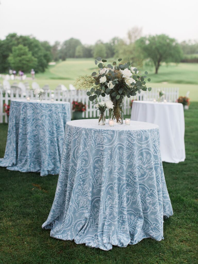 outdoor wedding cocktail hour with hightop tables decorated in white and blue patterned tablecloths