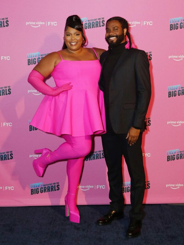 Lizzo and Myke pose on a red carpet. 