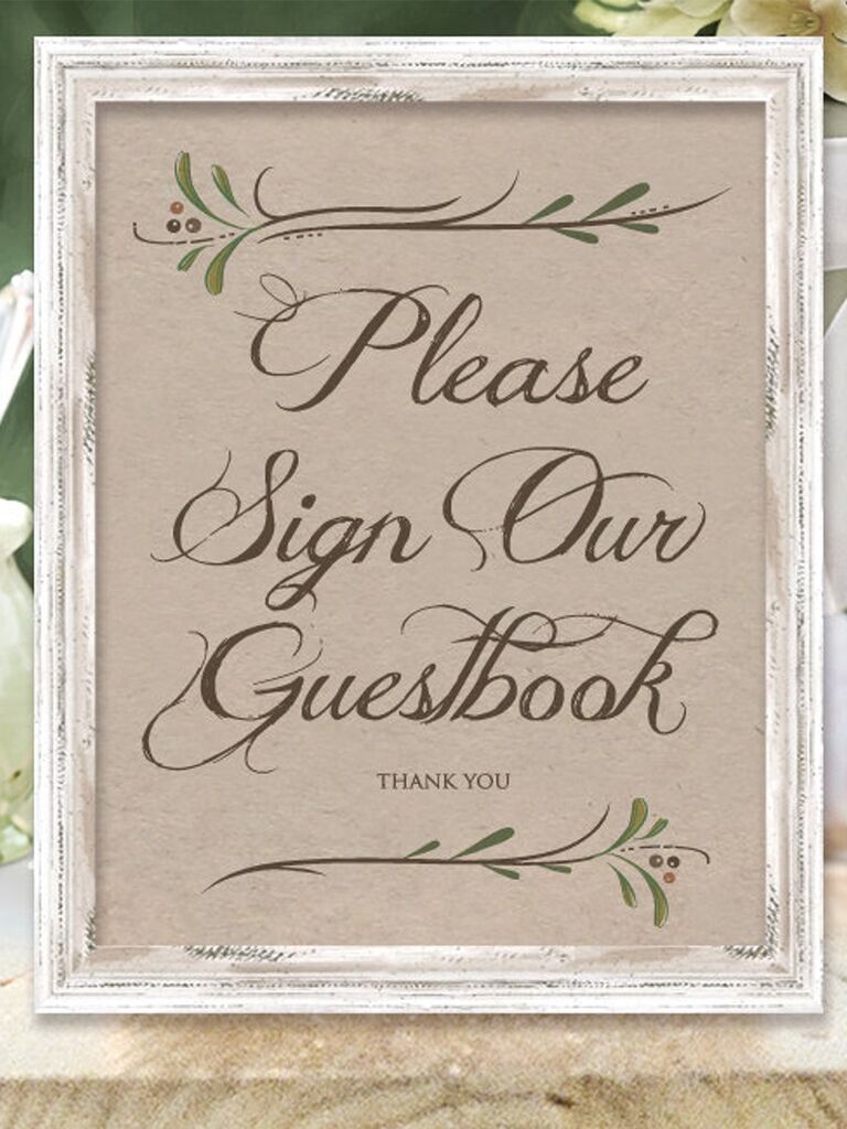 'Please sign our guestbook' in rustic script with sprig graphics on kraft paper in white frame