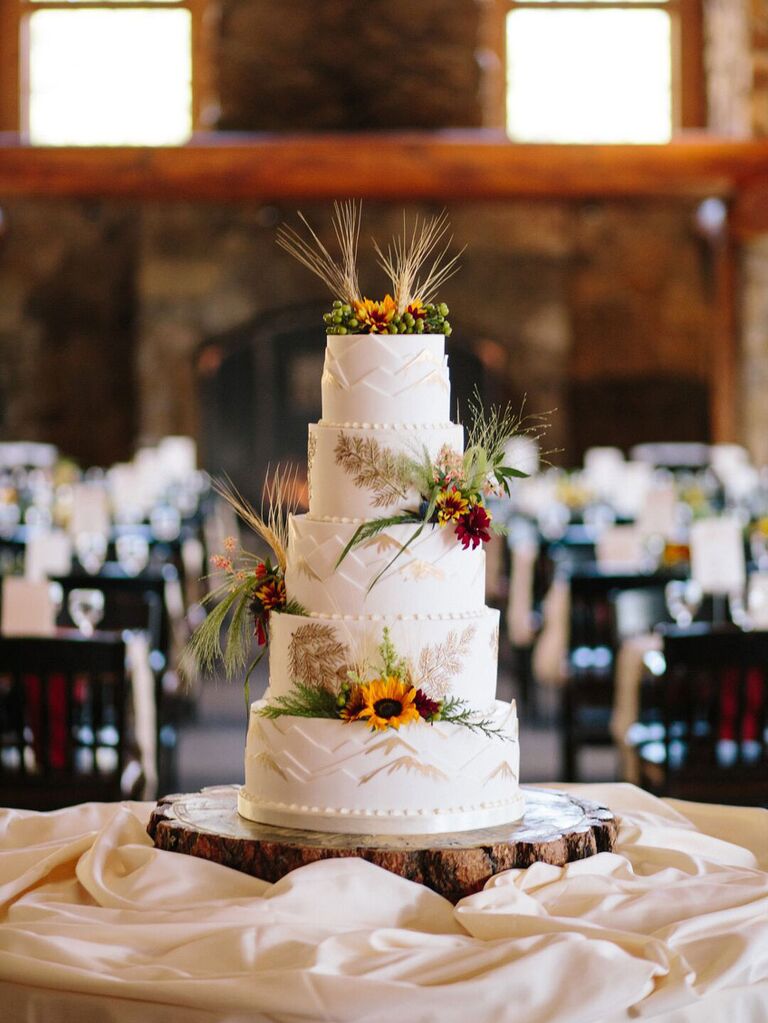 Five-tier rustic wedding cake with wildflower accents and grassy palms