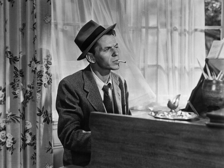 In a classic pose, Frank Sinatra smokes a cigarette as he plays piano