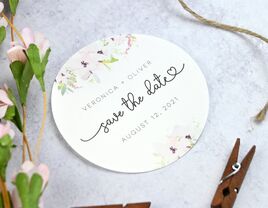 Circular white sticker with colorful floral details and Save the date written in black script