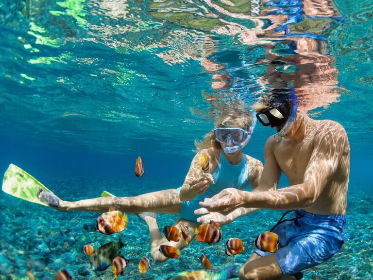 Young couple in snorkeling masks in coral reef sea pool