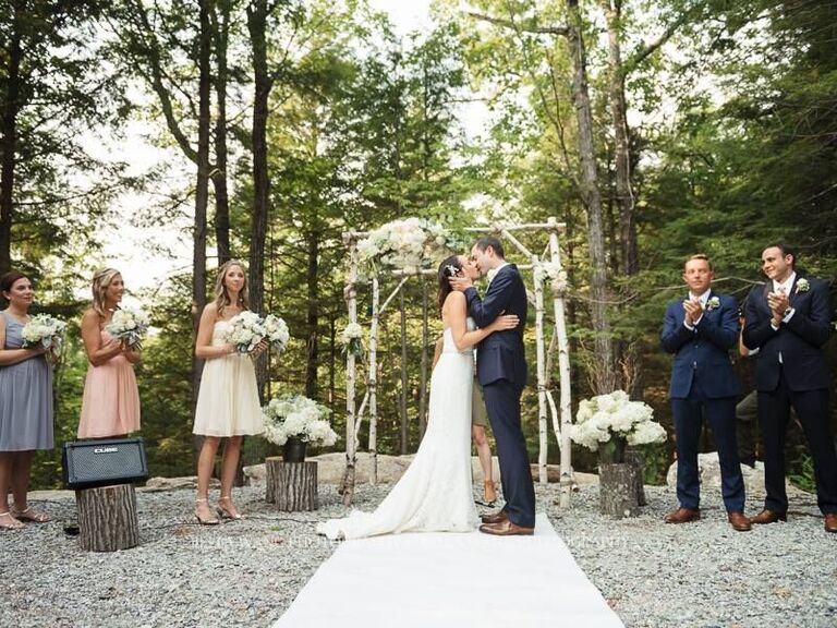 Couple kissing in the outdoor altar with wedding guests beside them