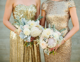 Two maids of honor in gold sparkly dresses holding bouquets