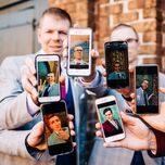 Groomsmen holding up phones with photos on the screens