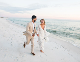 Couple running and smiling on beach, budget beach wedding ideas