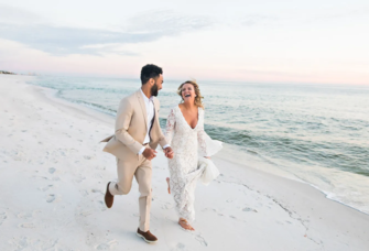 Couple running and smiling on beach, budget beach wedding ideas