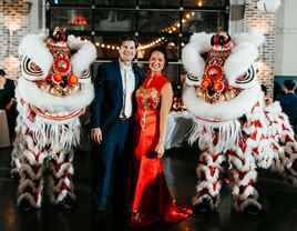 Bride and groom with traditional Asian lion dancers at wedding reception