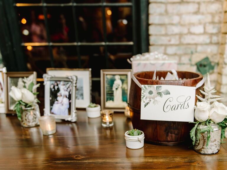 wedding welcome table decorated with framed family photos and wooden barrel repurposed as card box