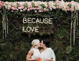 'Because Love' neon sign in simple type with couple kissing underneath