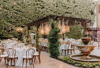 Whimsical garden bridal shower venue with hanging bistro lightng and stone water fountain