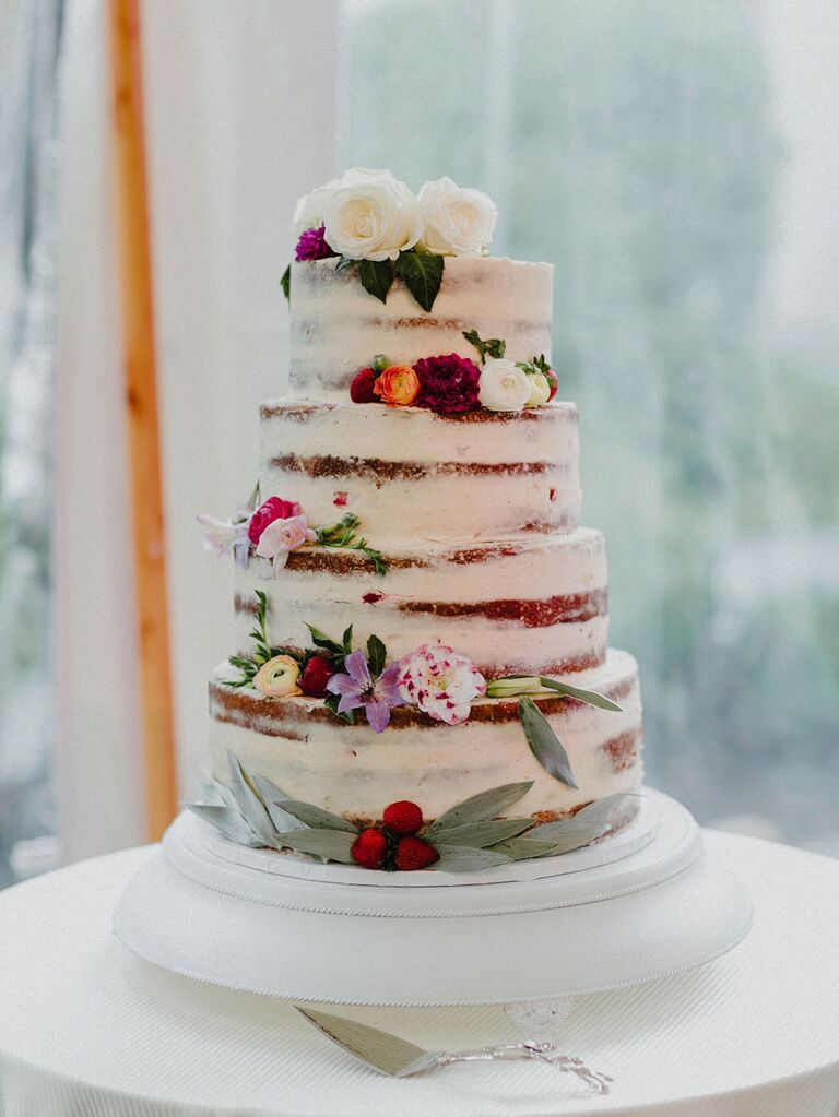 Semi-naked wedding cake with white icing and fresh flowers