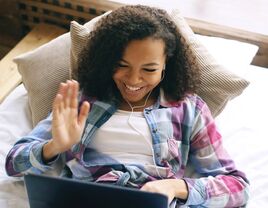 Woman waving to friend on laptop video chat 