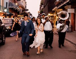 Happy couple dancing through the street with a brass band