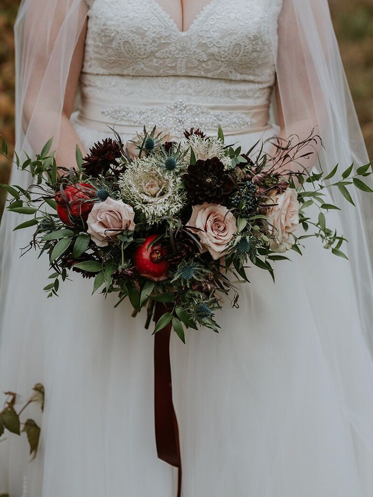 winter wedding bouquet with greenery, mauve roses, burgundy dahlias, blue thistle and pomegranates
