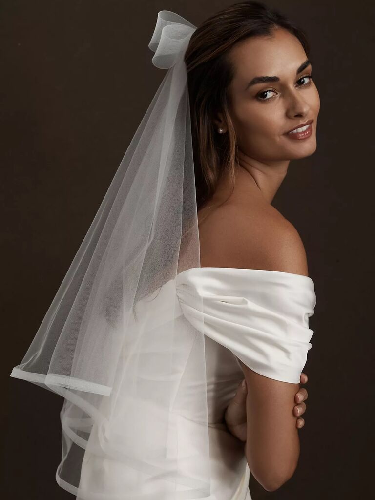 Model wears a bow-style veil with her hair pulled back. 
