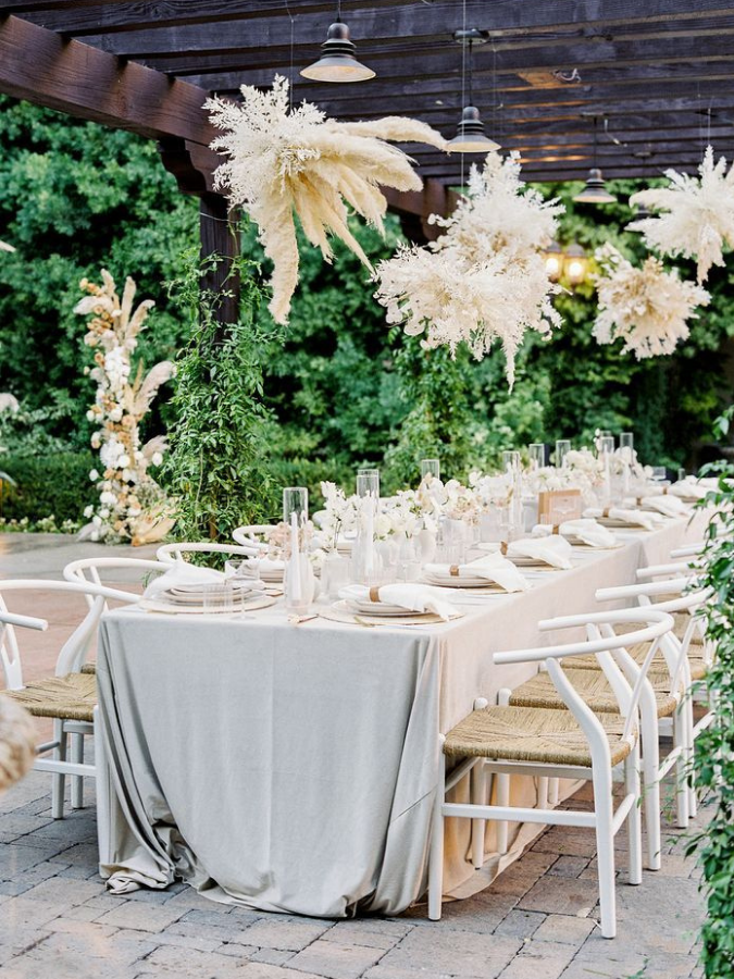 Boho reception tablescape under pergola with pampas grass chandeliers