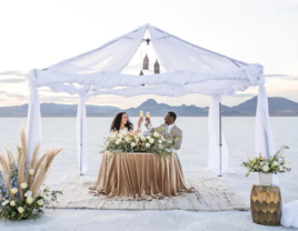 Bride and groom at sweethearts table under tent from Diamond Event & Tent rentals in Utah