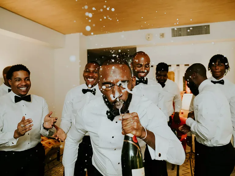 Groomsmen and Groom Getting Ready in Tuxes, Spraying Champagne in Groom's Face