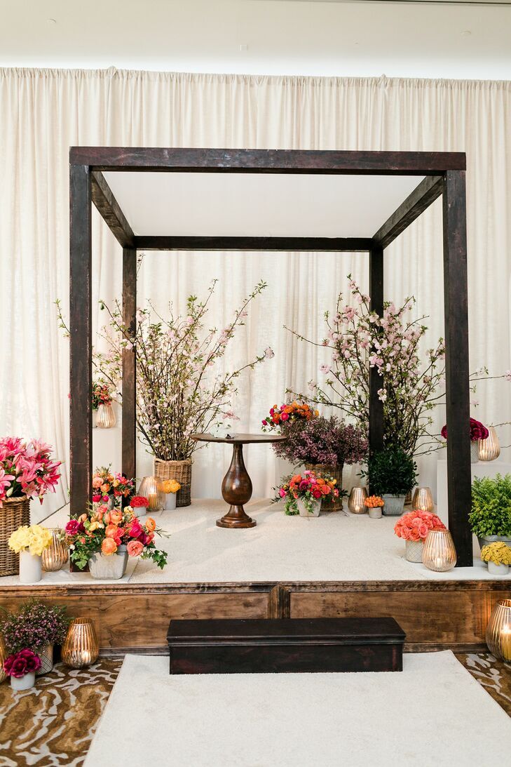 Black chuppah decorated with groupings of floral arrangements. 