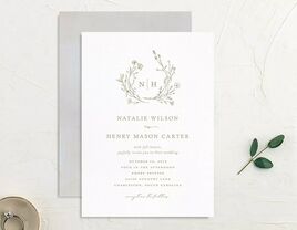 Monogram framed by greenery above event details with classic gray type on white background