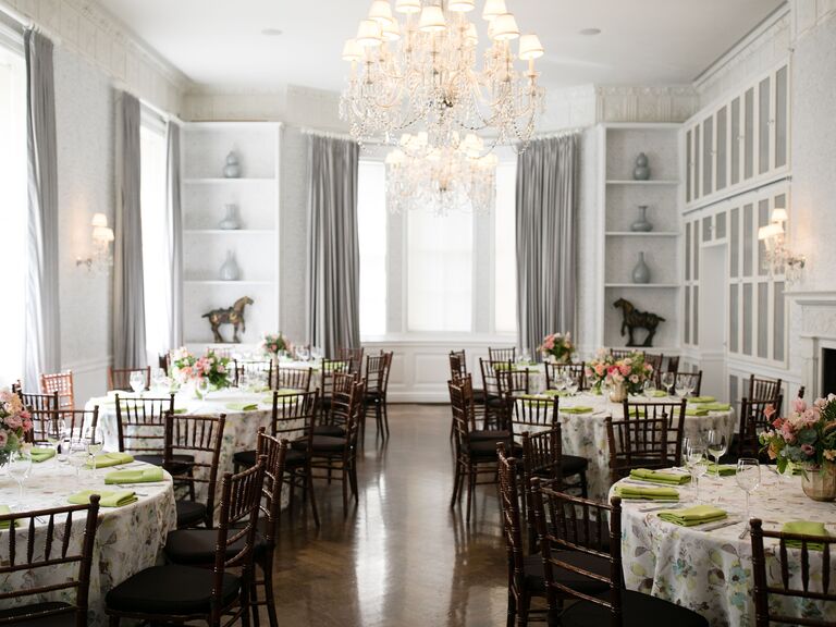Intimate reception space with white walls, a large crystal chandeliers, tables and chairs