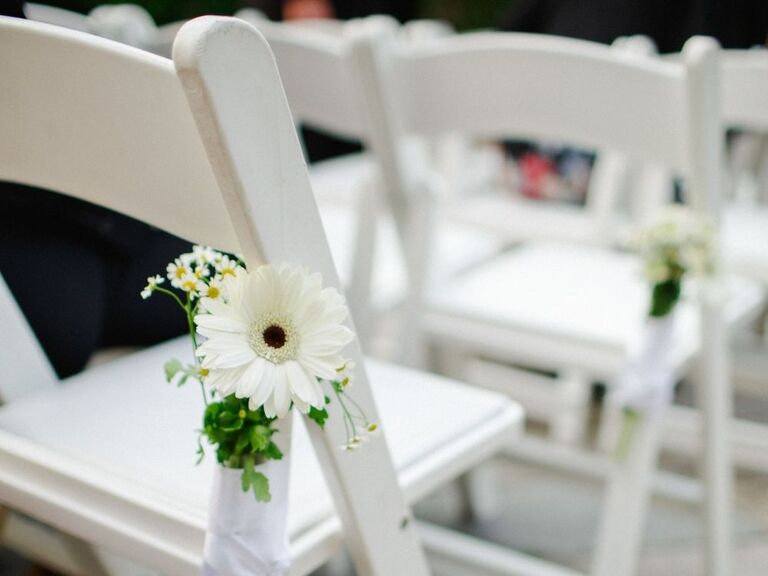 White folding chairs decorated with white daisy flowers