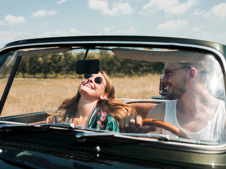 Couple driving in car smiling on road trip