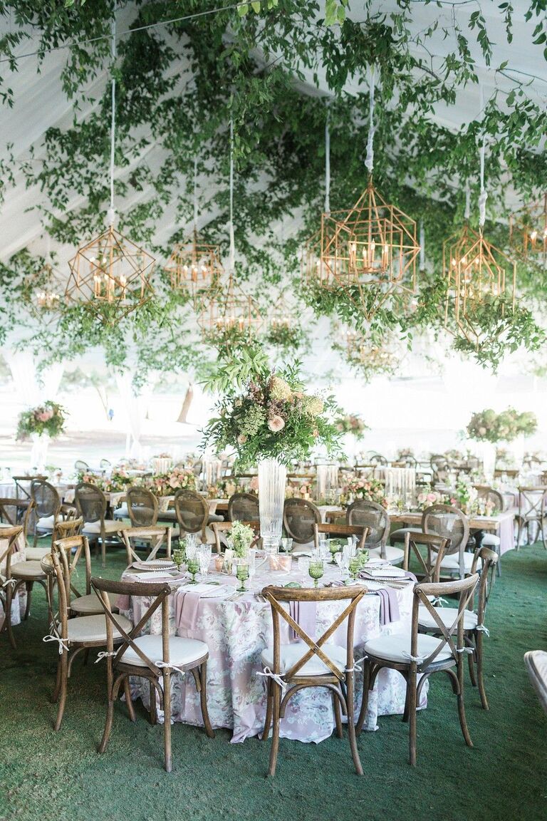 Greenery hanging in the tent at Green Acres with chandeliers and tall  flower centerpieces - Floral V Designs